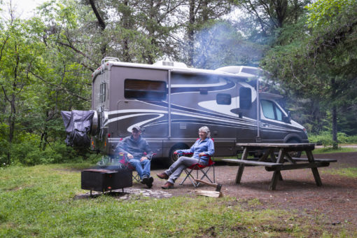 Couple relaxing near campfire. Road trip in motor home. North America.
