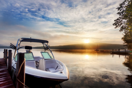 A power boat parked at a dock on a lake during sunrise.